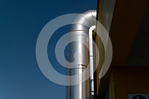 large luminous steel tubes, alongside a technical building, ventilation system pipes in the building.