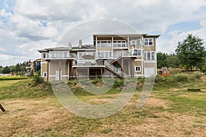 Large luxury home with blue sky and green grass yard multi-level exquisite