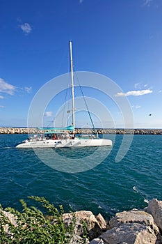 Large, luxury white catamaran leaving Puerto Banus harbour