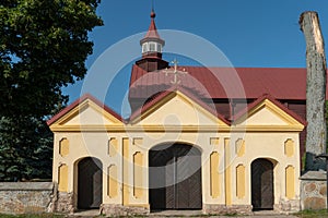 A large main gate at the entrance to a church or monastery. The old church after the restoration is surrounded by a stone fence