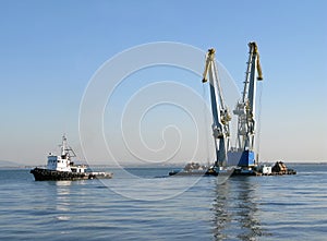 Large maritime cranes towed by boat