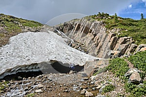 a large melting glacier on the side of a mountain peak. Mountain waterfall formed from a melting glacier