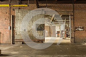 Large metal barn door left open in the basement level of an abandoned factory