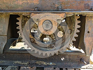 Large metal crane gear, rust-covered iron on construction equipment close-up on a summer day with bolts and nuts on rails