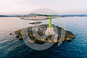 A large metal green lighthouse on a rock in the sea, near Cape Punta Planka in Croatia.