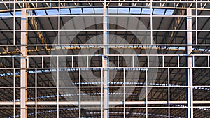 Large metal industrial factory building structure with corrugated steel curve roof and skylights in construction site area