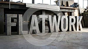 Large metal letters spelling flatwork in workshop