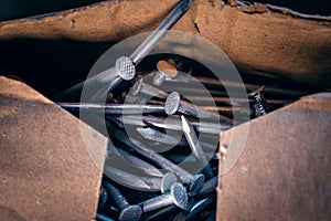 Large metal nails in a cardboard box close-up. Universal building material for fastening and tying wooden parts