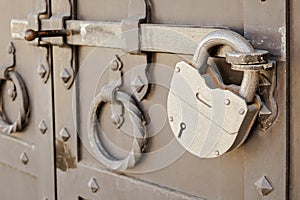 Large metal padlock on a heavy metal door with a deadbolt