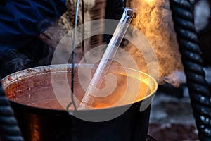 Large metal soup pot on an open fire at an open-air Christmas market, street food, close-up