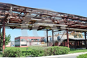 A large metallic iron pipeline trestle with pipes and wires for electricity in a petrochemical chemical refinery in the