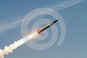 A large military ballistic rocket is flying through the blue sky