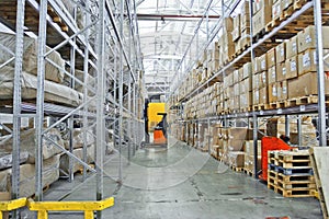 Large modern warehouse with forklifts, shelves with pallets, boxes, containers and goods