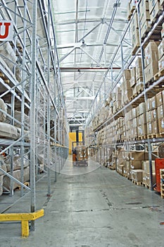 Large modern warehouse with forklifts, shelves with pallets, boxes, containers and goods