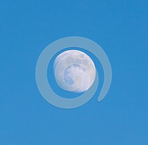 A large moon is in the sky above a blue sky
