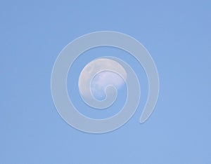 A large moon is in the sky above a blue sky