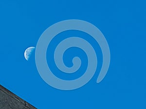 A large moon is visible in the sky above a blue sky