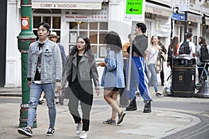 A large motley crowd walks up Bricklane on a Sunday afternoon. The flea market on Bricklane works on Sundays.