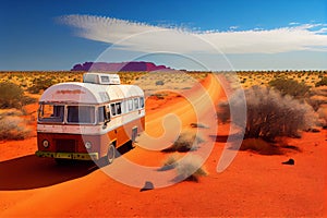 Large motorhome bus driving in the arid Australian outback. Red dirt road. Lap of Australia