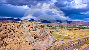 Large mountains with house on hill in desert next to roads