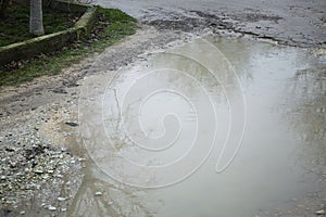 A large muddy puddle on the road on a rainy day. Close-up. Hopelessness and dirt. Space for text