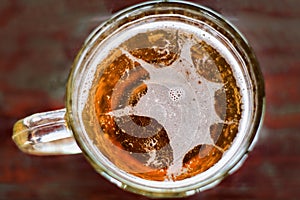 Large mug of beer with foam and bubbles top view with the sun