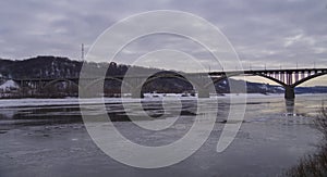 A large multi-span arch bridge over a frozen river. Landscape with a long arched bridge.