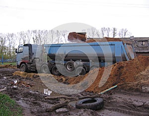 Large multi-ton truck stuck in mud loads manure on farm slips
