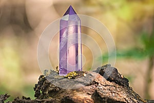 Large mystical faceted quartz crystal on a stump on a background of nature close-up