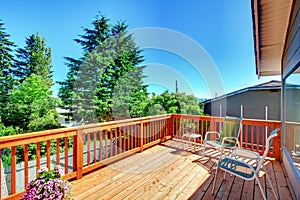 Large new wood deck home exterior with chairs.