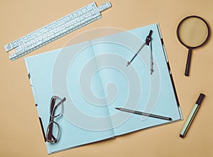 A large notebook for notes and drafting with stationery objects for a student on a yellow background. Ruler, marker, pencil