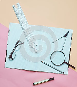 A large notebook for notes and drafting with stationery objects for a student on a yellow background. Ruler, marker, pencil