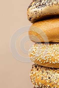 Large number of different bagels in hands on a beige background