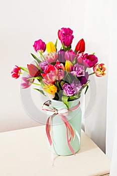 Multicolor tulips in metal vase on white background