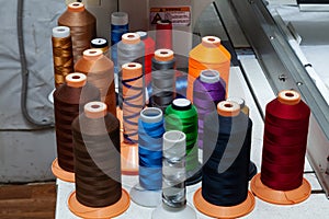 A large number of reels with colored threads in a workshop for sewing and hauling textiles for the automotive industry and