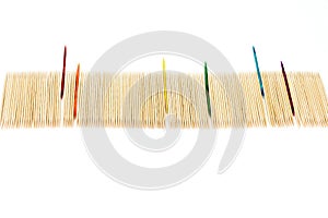 Large number of toothpicks lined up in a long row, with rainbow colored toothpicks sticking out, isolated on white