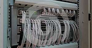 Large number of wires and cables in modern server and network equipment with flashing green lights and optical severs computer in