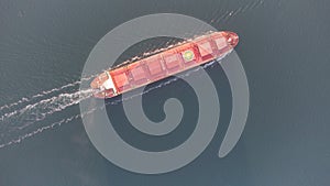 A large ocean-going cargo ship moves out to sea on calm waters. Dry cargo ship aerial view