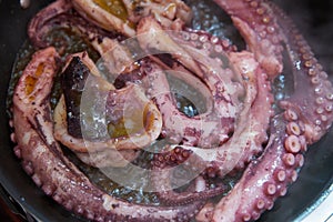 The large octopus is fried on a frying pan, Feelers of violet color, close-up