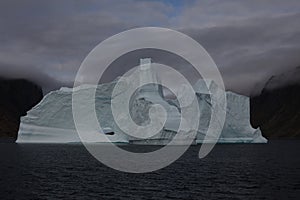 A large and oddly shaped iceberg drifts in a fjord in northwest Greenland