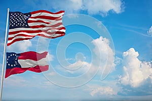 Large official Flag of US with smaller flag of the Confederate States of America 1861-1863 at cloudy sky background. United states