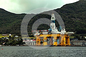 Large offshore oil rig drilling platform in Norway behind the mountains
