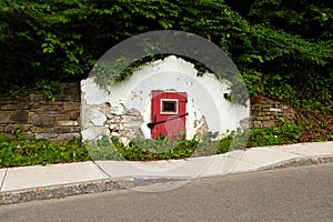 Large old 19th Century plastered stone white root cellar with screened window in its red door