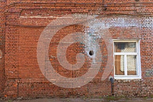 Large old dilapidated red brick house with a white window. Old dirty abandoned factory building