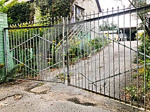 Large old iron metal gate door made of twigs at the entrance to the house