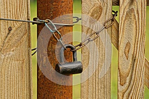 A large old padlock and chain on a pipe and a wooden board