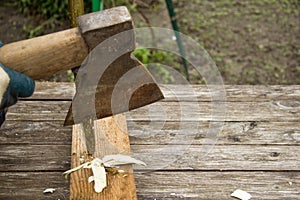 A large old rusty axe cut a thin branch of wood on a wooden table. Place for inscription