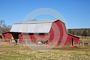 A large old weathered red painted barn and a tin roof.