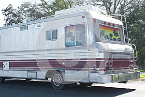 Large older late model vintage RV recreational vehicle driving down a paved road or highway. downsizing lifestyle. independent