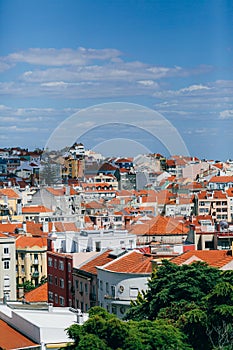 A large orange building with a mountain in the background. View of the rooftops of Lisbon. Portugal